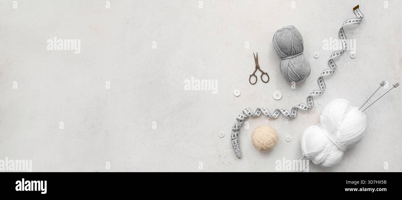 Yarn balls, scissors, buttons, measuring tape and knitting accessories on light background with space for text Stock Photo