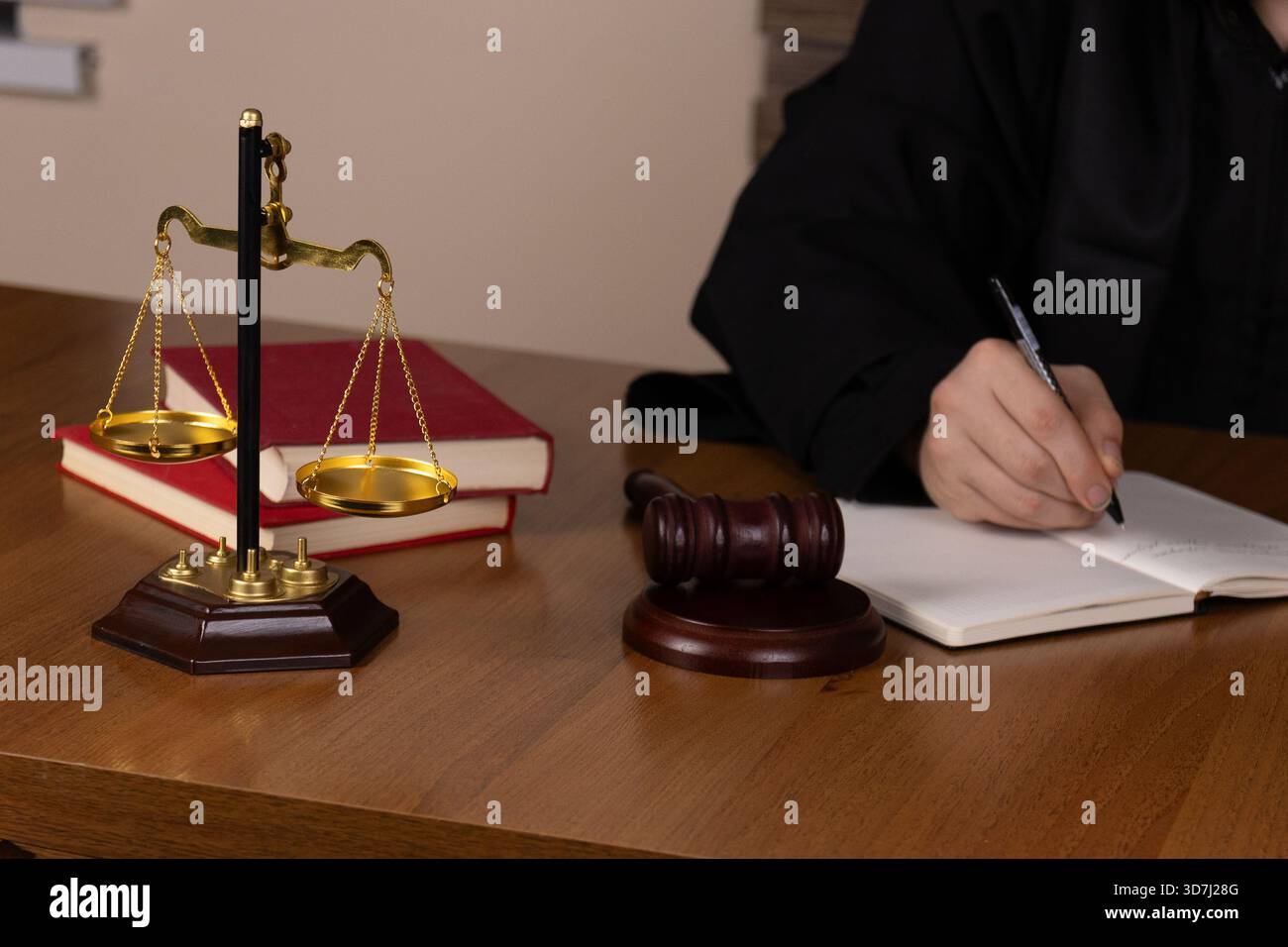 Justice Written A judge is writing notes at a desk with a scale of justice and books ...