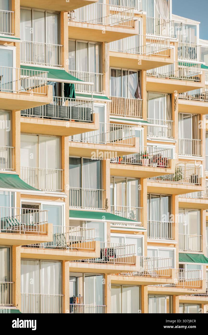 Geometric stacked balconies with green awnings on a multi-story apartment building, creating a complex, repetitive visual pattern Stock Photo