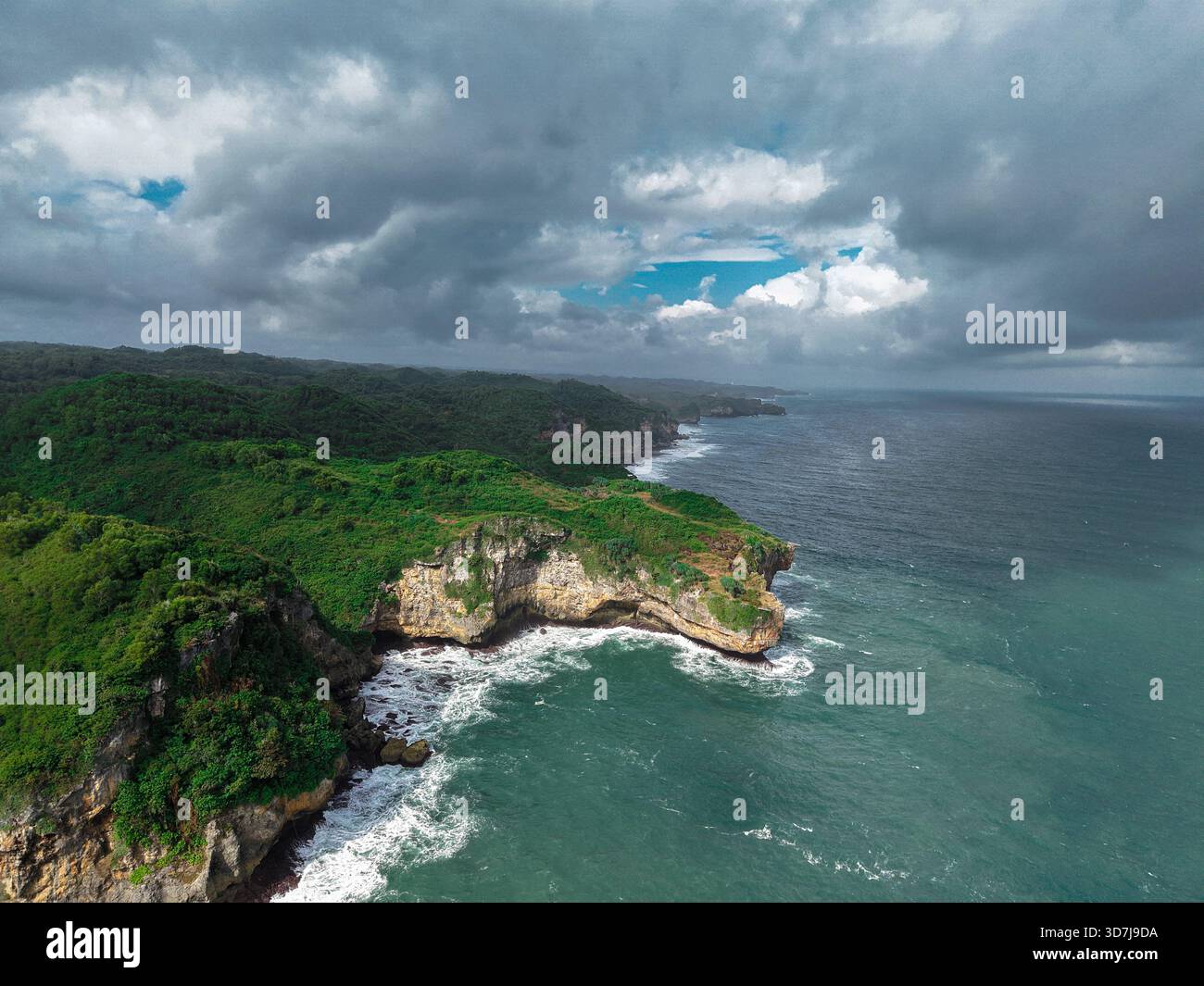Aerial view of rugged green coastal cliffs with waves crashing below ...