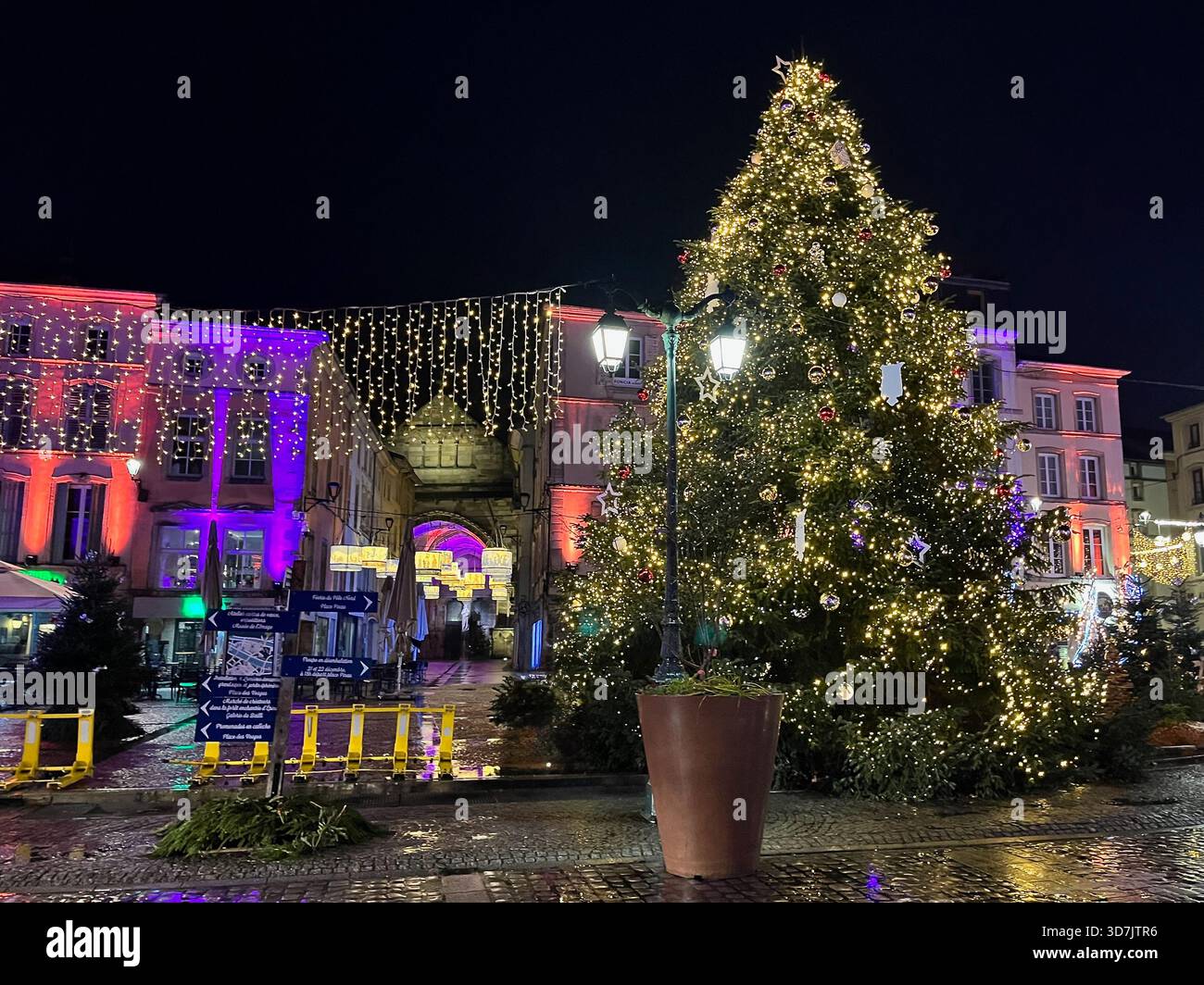 Épinal, France – 2 December 2024: A large illuminated holiday tree and glowing streetlights decorate the central square at night, with buildings - Smartphone Captured Stock Image