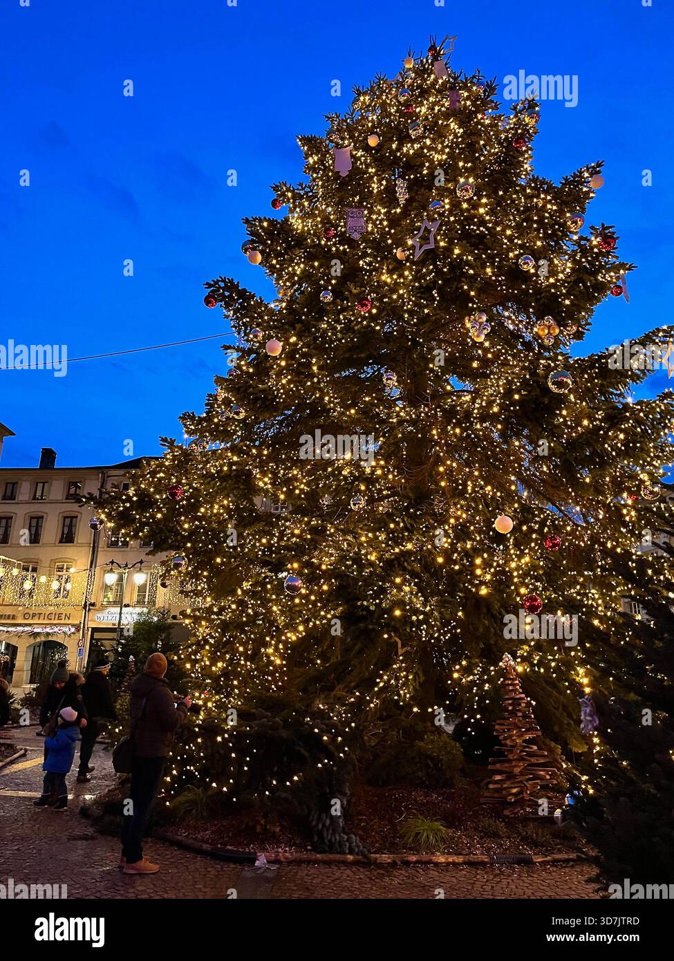Épinal, France – 2 December 2024: A large illuminated holiday tree and glowing streetlights decorate the central square at night - Smartphone Captured Stock Image