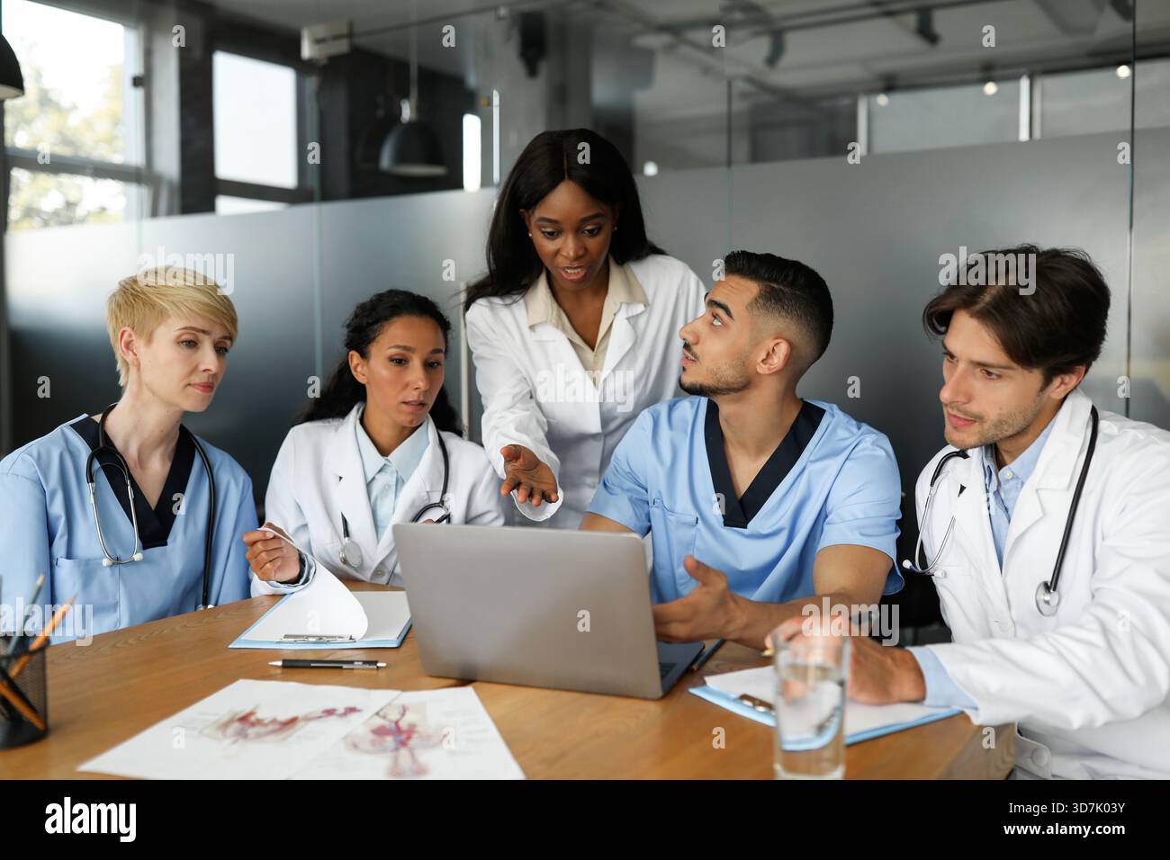 Puzzled doctors discussing medical cases, using laptop Stock Photo