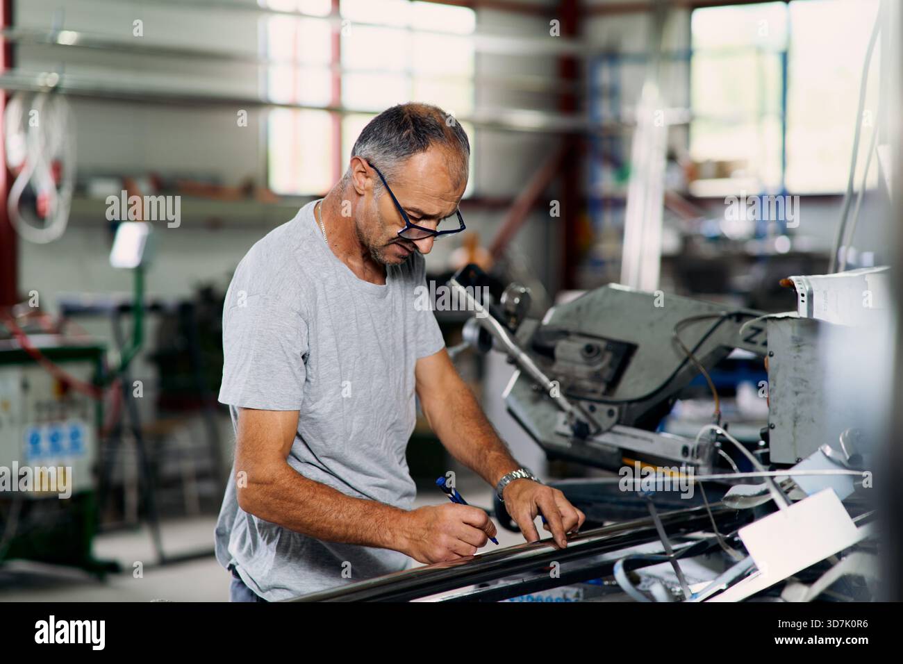 Factory worker examining metal material in industrial workshop ...
