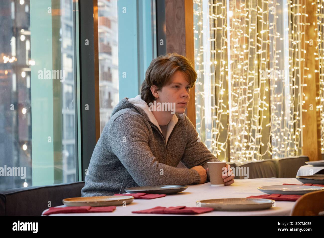 Thoughtful handsome young man waiting and drinking coffee in cafe and looking away. Stock Photo