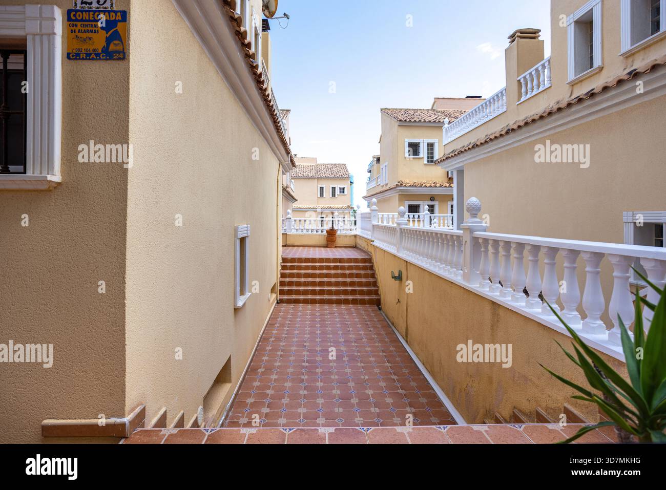Terracotta tiled path and stairway framed by cream buildings and ...