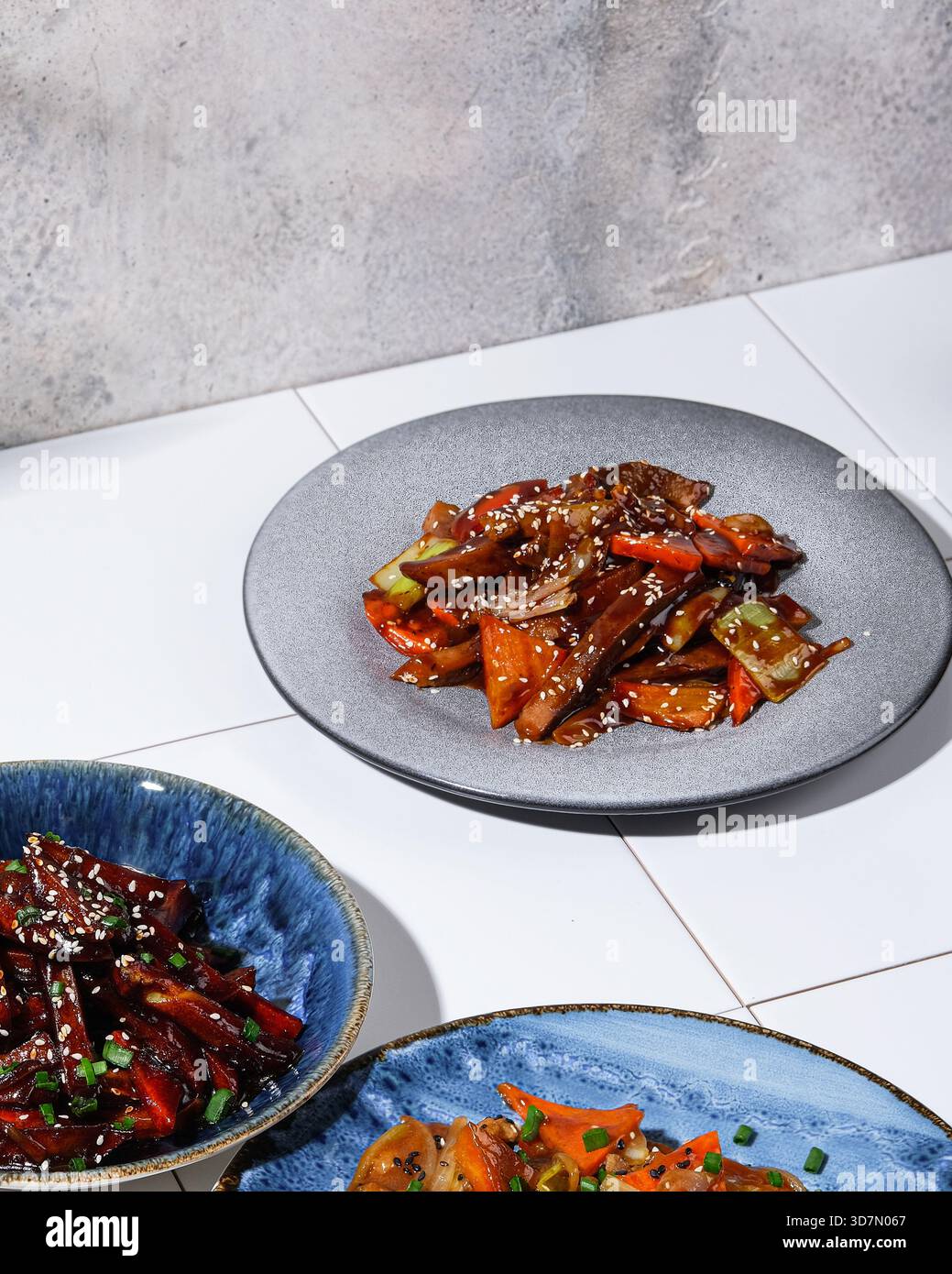 Shared dishes featuring glazed sesame beef and fresh herbs Stock Photo