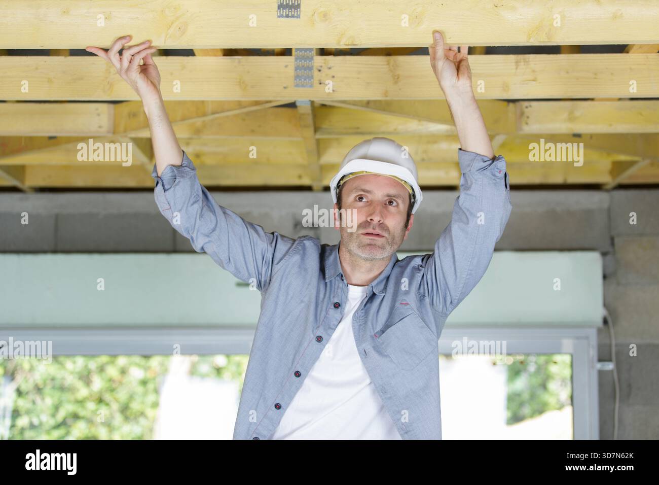 a male worker checking a wood ceiling Stock Photo