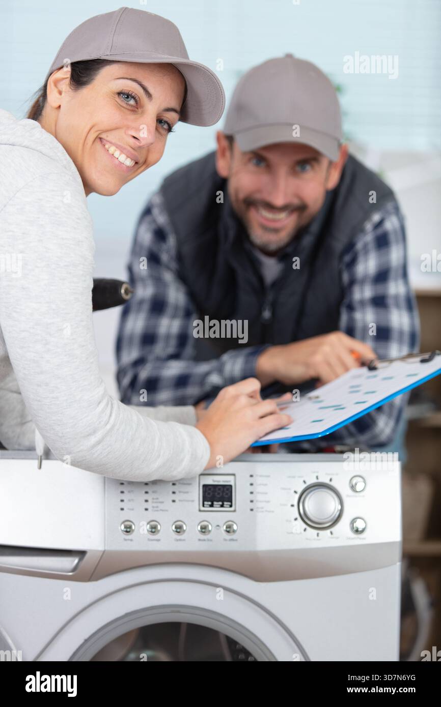 female and male plumber repairing washing machine Stock Photo