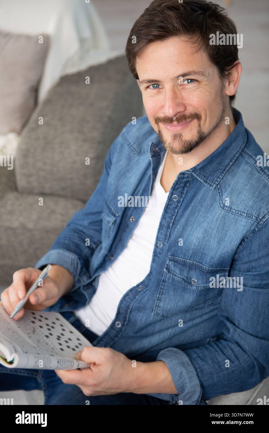 young man sitting doing a crossword puzzle Stock Photo