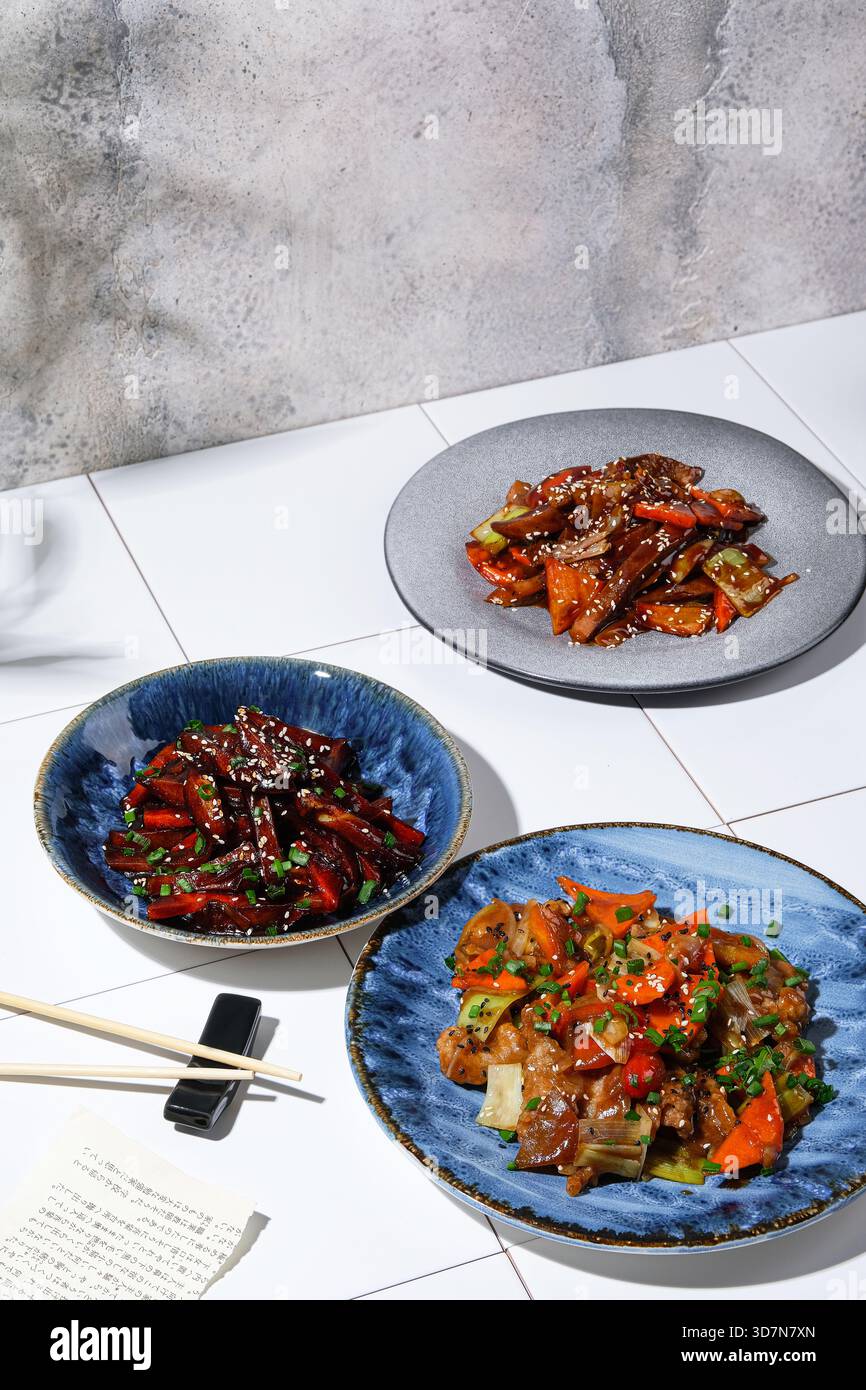 Casual lunch featuring spicy vegetables and glossy sauces with chopsticks Stock Photo