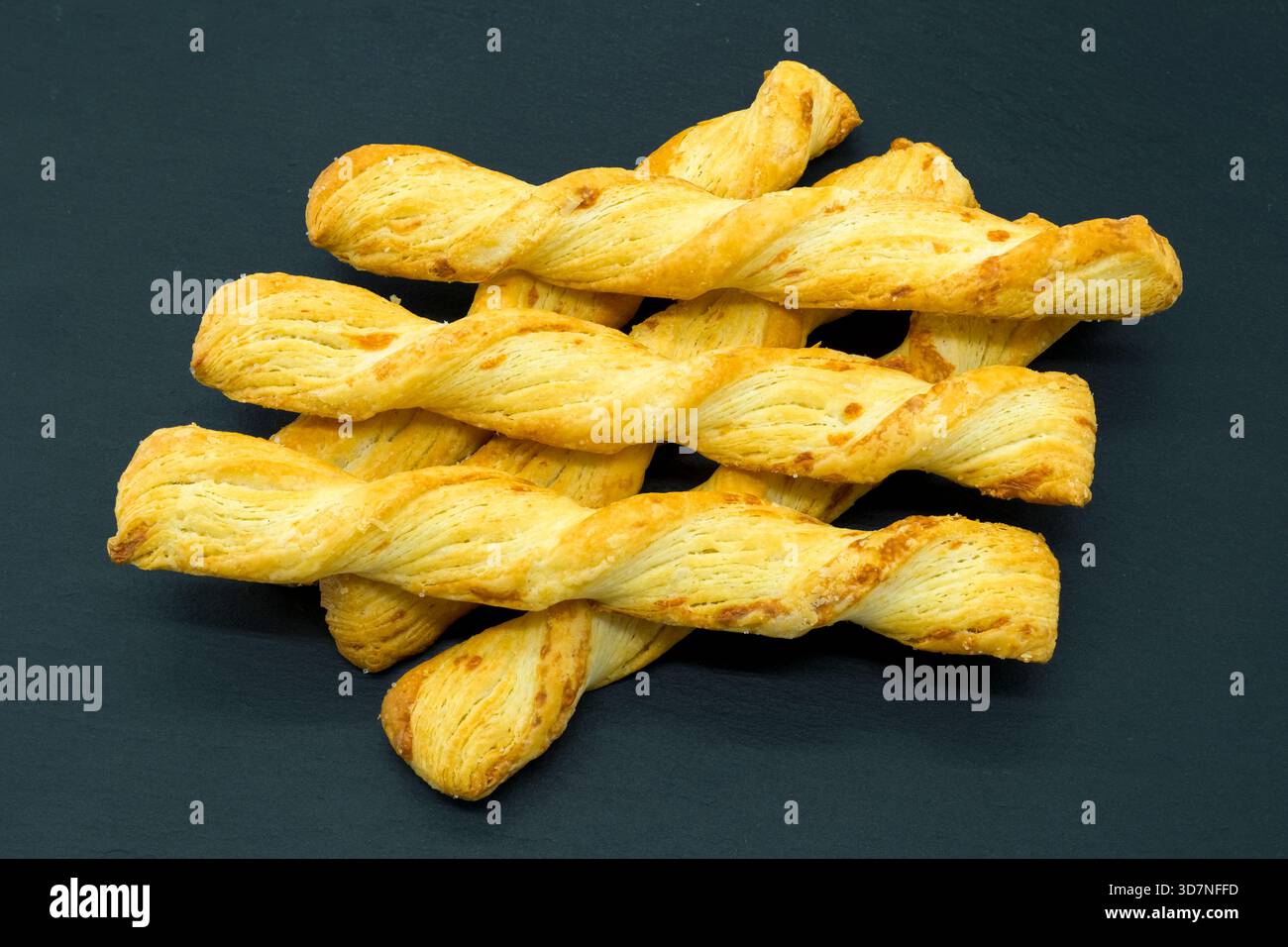 Crusty Bread Sticks or twists cooling on a slate board and ready to eat straight out of the oven. Stock Photo