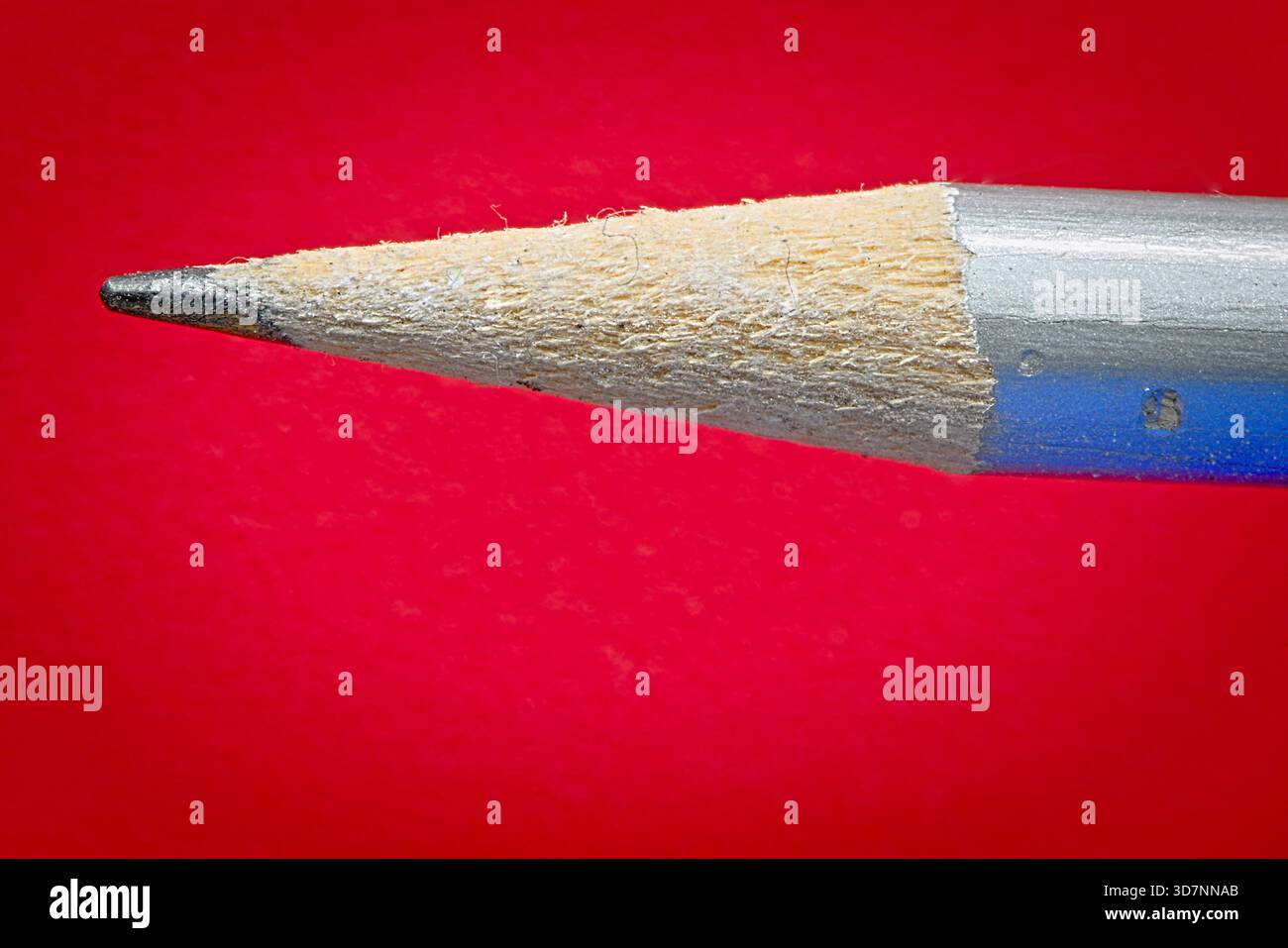 Sharpened pencil point on red background Stock Photo