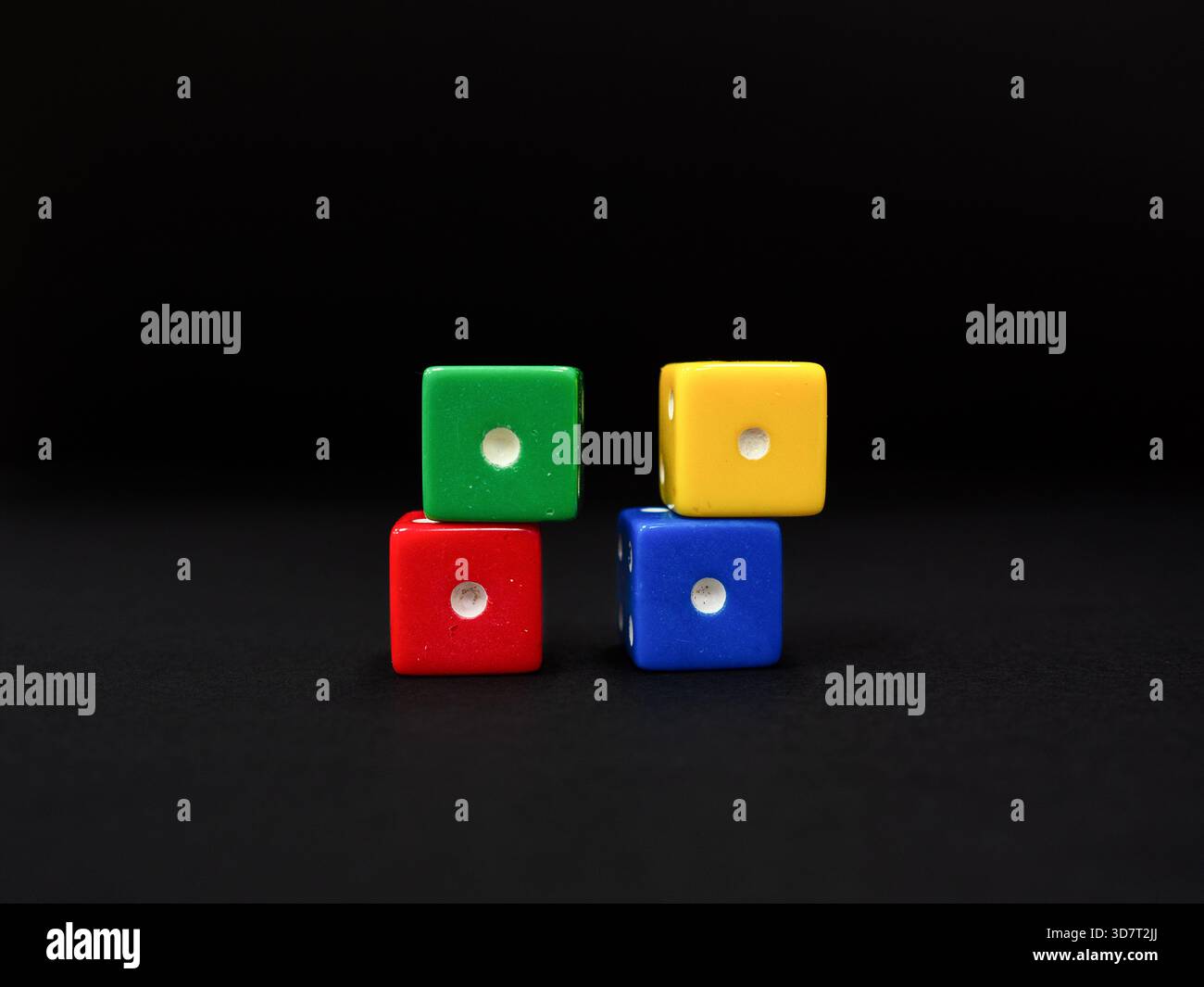 Colored dice  scattered on a uniform dark black background. Stock Photo