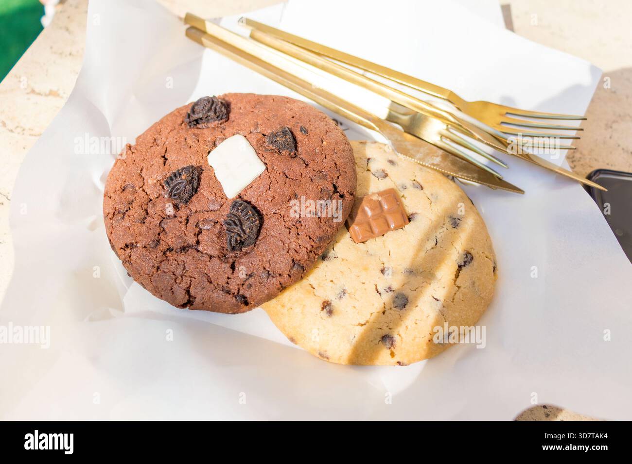 Two large soft cookies with chocolate chips on white paper close-up. Stock Photo