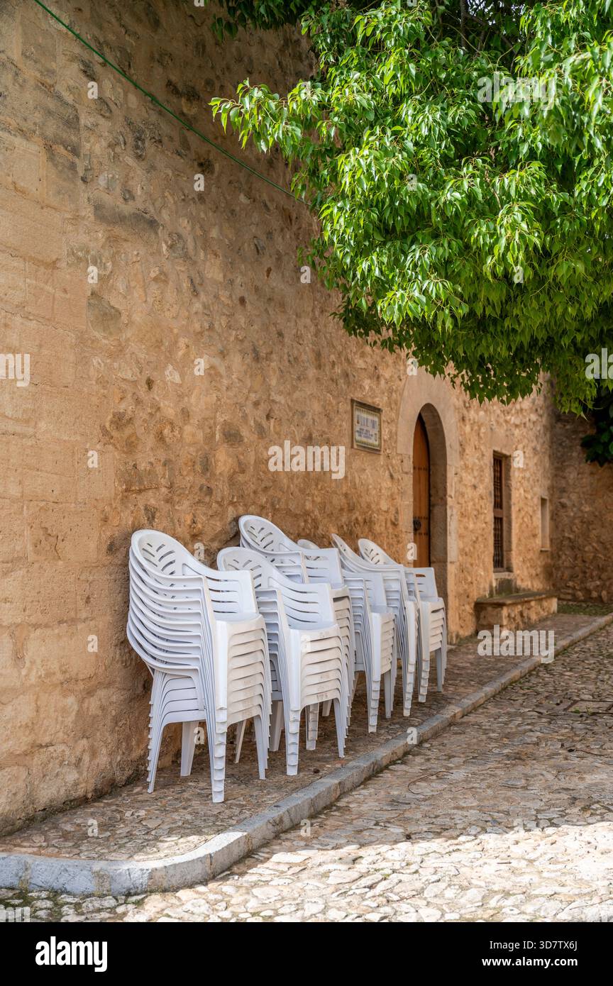 Plastic chairs stacked by old stone wall in Sencelles, market day, Mallorca Stock Photo