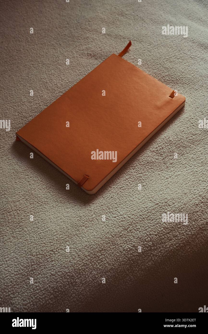 Orange leather notebook mockup on white textured surface. Stock Photo