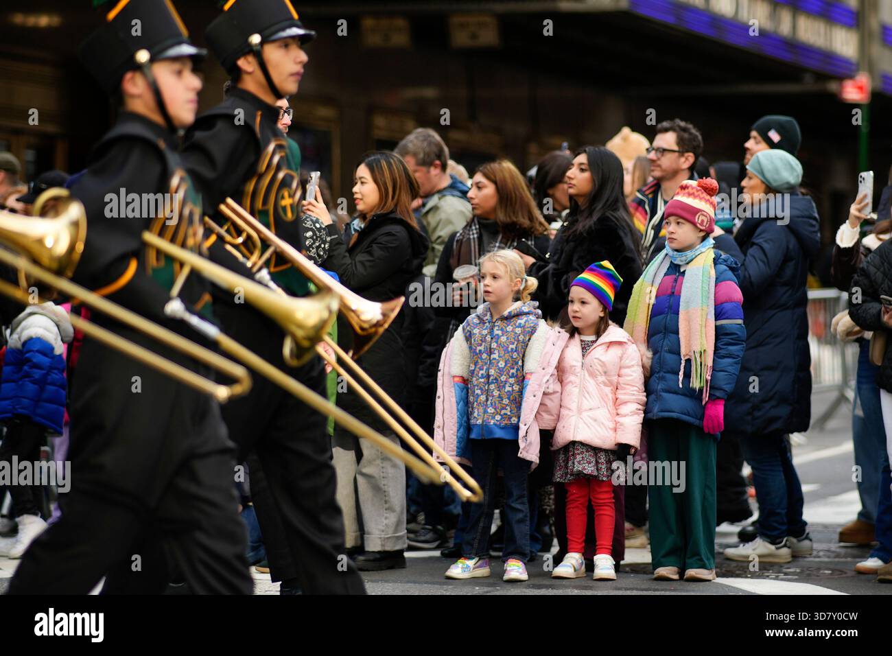Spectators watch as a marching band passes by during the Macy's ...