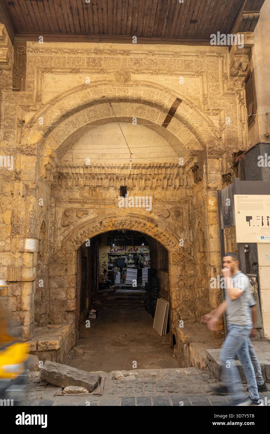 Transient, blurred humans contrast with the solidity of the Wikala of Nafisa al-Bayda in historic Cairo, Egypt, unusual as it has a sculpted face. Stock Photo