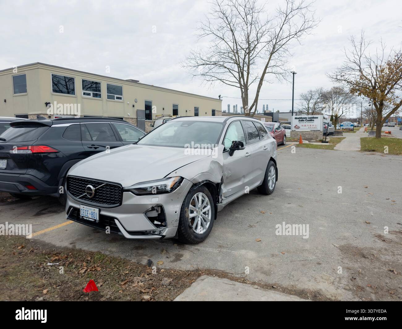 Damaged silver Volvo SUV with dented fender and dislodged bumper parked in Ajax commercial lot. - Smartphone Captured Stock Image
