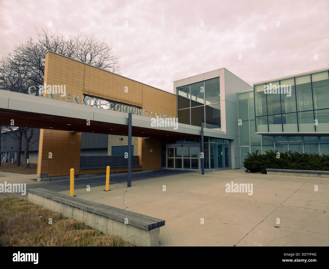 Centennial College building with glass panels, brick facade, bollards, and landscaped entrance under overcast sky. - Smartphone Captured Stock Image
