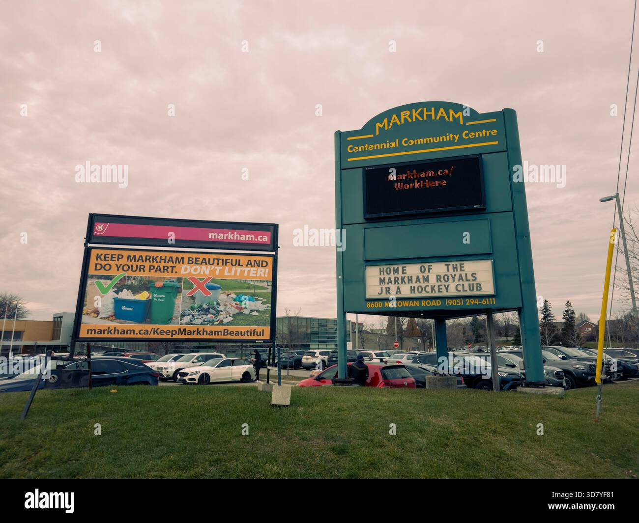Community centre signs promote anti-littering, local hockey, and city job opportunities in grassy plaza. - Smartphone Captured Stock Image
