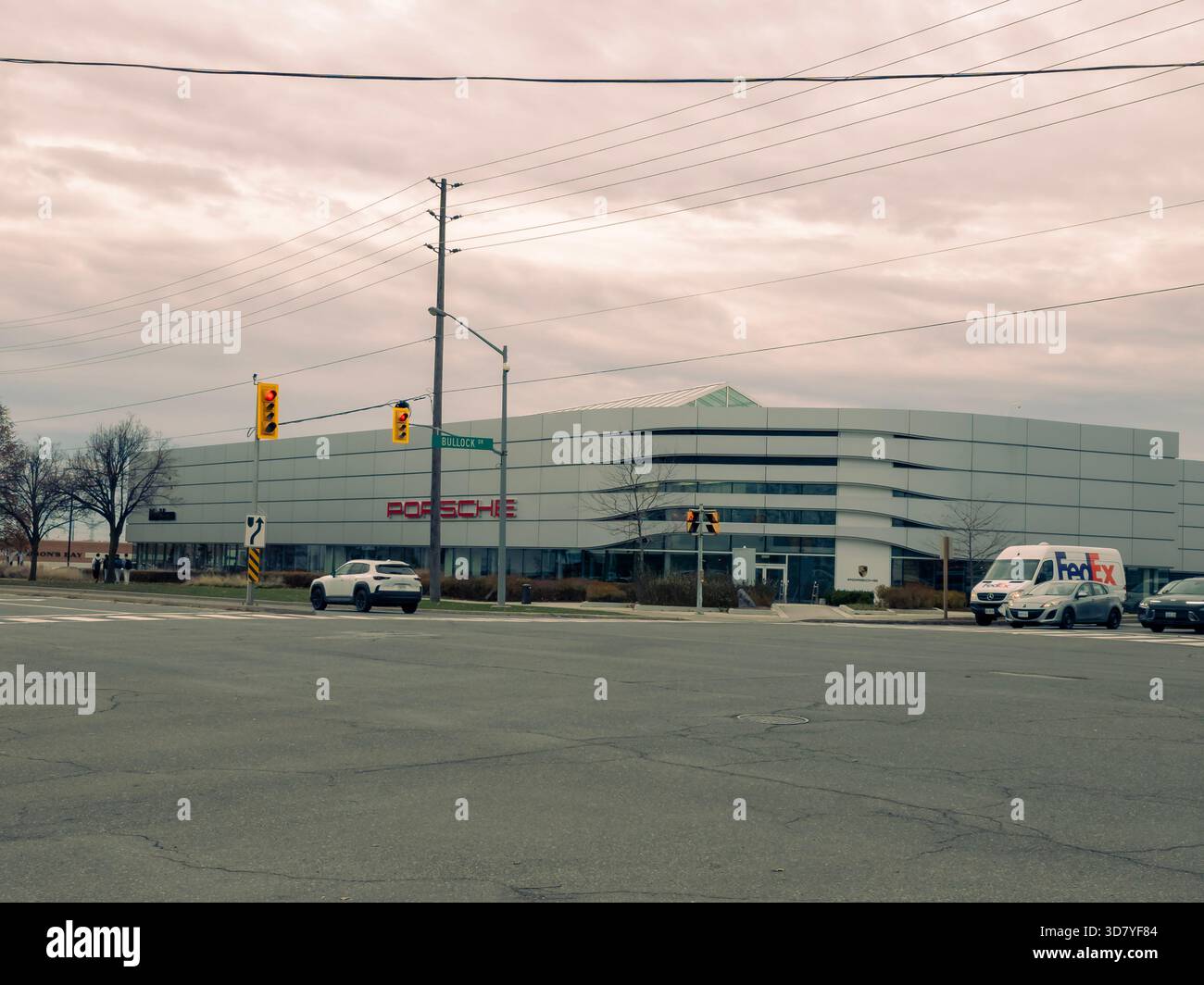 Porsche dealership at Bullock Drive with red logo, glass facade, traffic lights, and pedestrians. - Smartphone Captured Stock Image