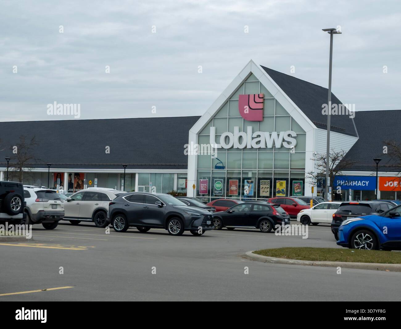 Loblaws grocery store and GoodLife Fitness in suburban plaza with parked cars under overcast sky. - Smartphone Captured Stock Image
