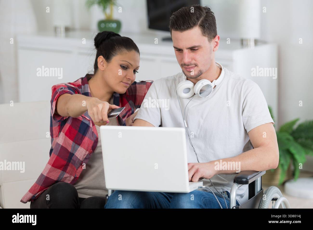 disabled man using laptop sitting next to his girlfriend Stock Photo