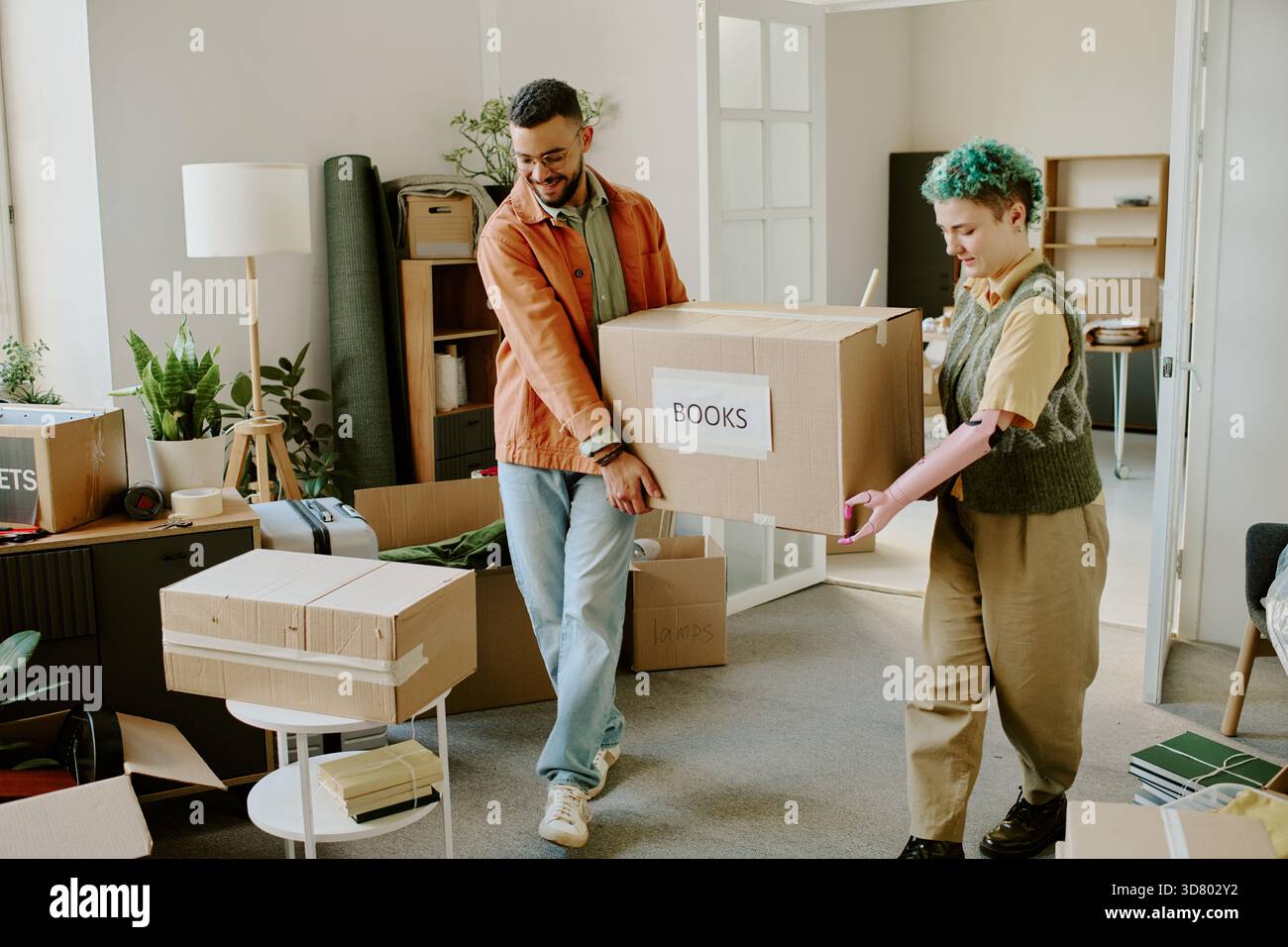 Young Multiethnic Couple Carrying Boxes While Moving and Renovating Apartment Stock Photo