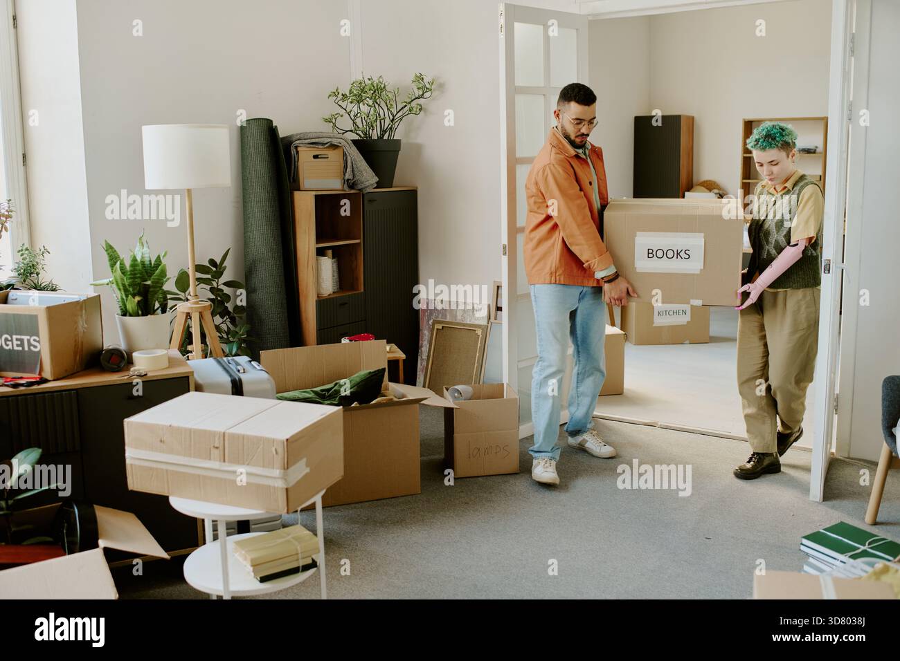 Young Multiethnic Couple Carrying Boxes While Moving into New Apartment Stock Photo
