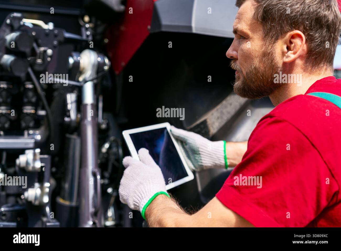 Farm machinery technician using tablet for equipment diagnostics Stock Photo