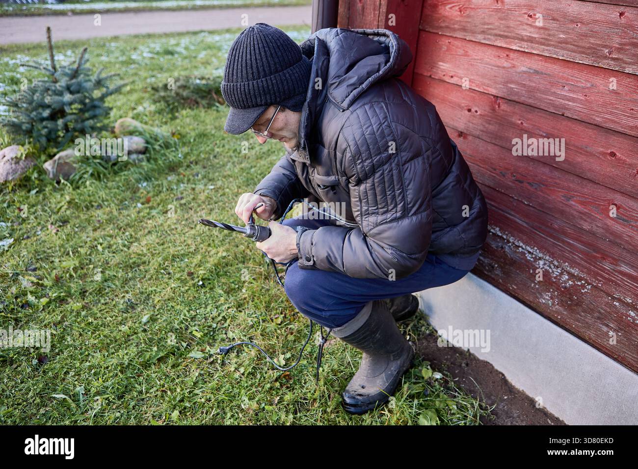Before carrying out external installation work, repairman secures drill bit using chuck key. Stock Photo