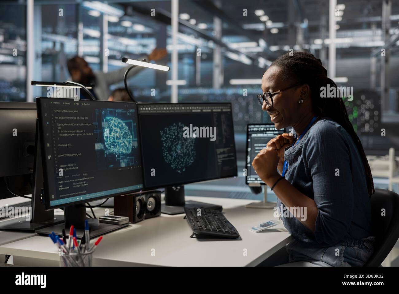 Happy engineer in data center using AI powered tech to run simulations. Cheerful employee coding cognitive computing algorithms to extract insights from data and automate rigs Stock Photo