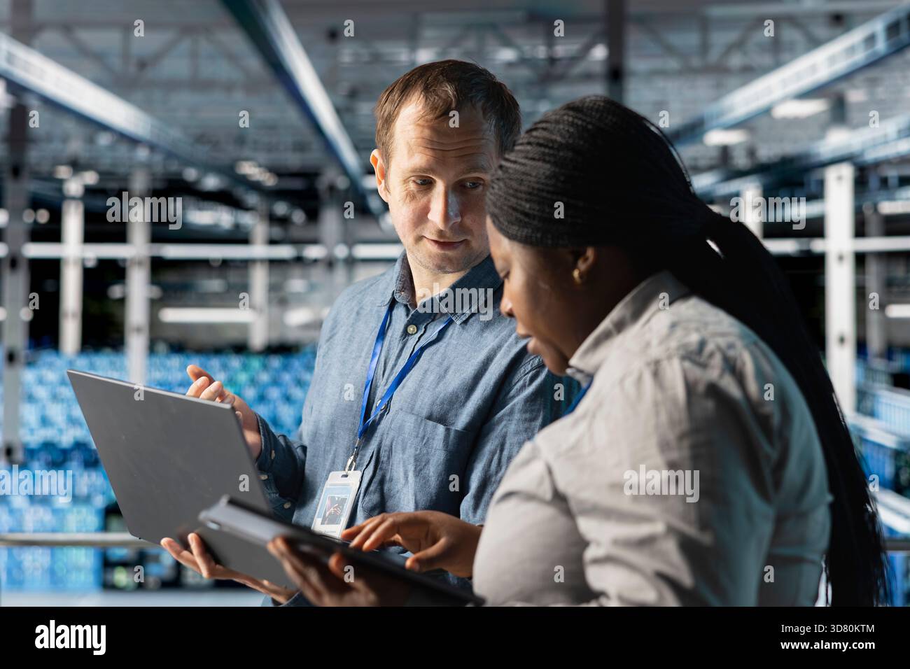 Server room coworkers auditing systems for vulnerabilities using software on laptop. Teamworking data center technicians coordinating backups and recovery protocols using notebook Stock Photo
