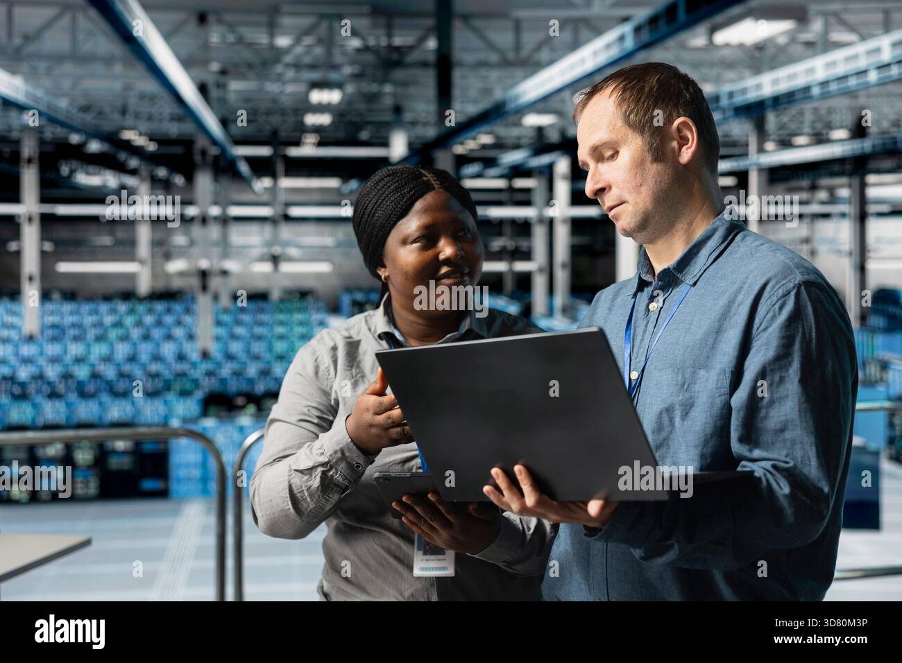 Data center computer scientists doing brainstorming, using laptop to manage system stability. Server room colleagues optimizing performance with device, configuring equipment Stock Photo
