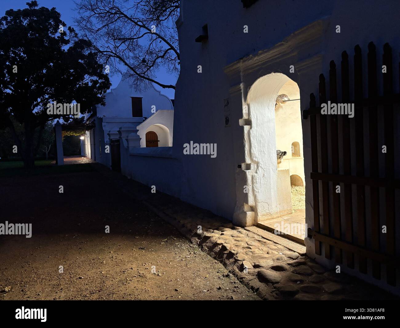 Night scene of a historic white building with Cape Dutch architectural details illuminated by warm artificial lighting. - Smartphone Captured Stock Image