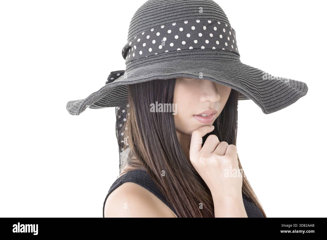 Attractive elegant asian young woman with covered half face by black hat. Close-up portrait. Isolated on the white background Stock Photo