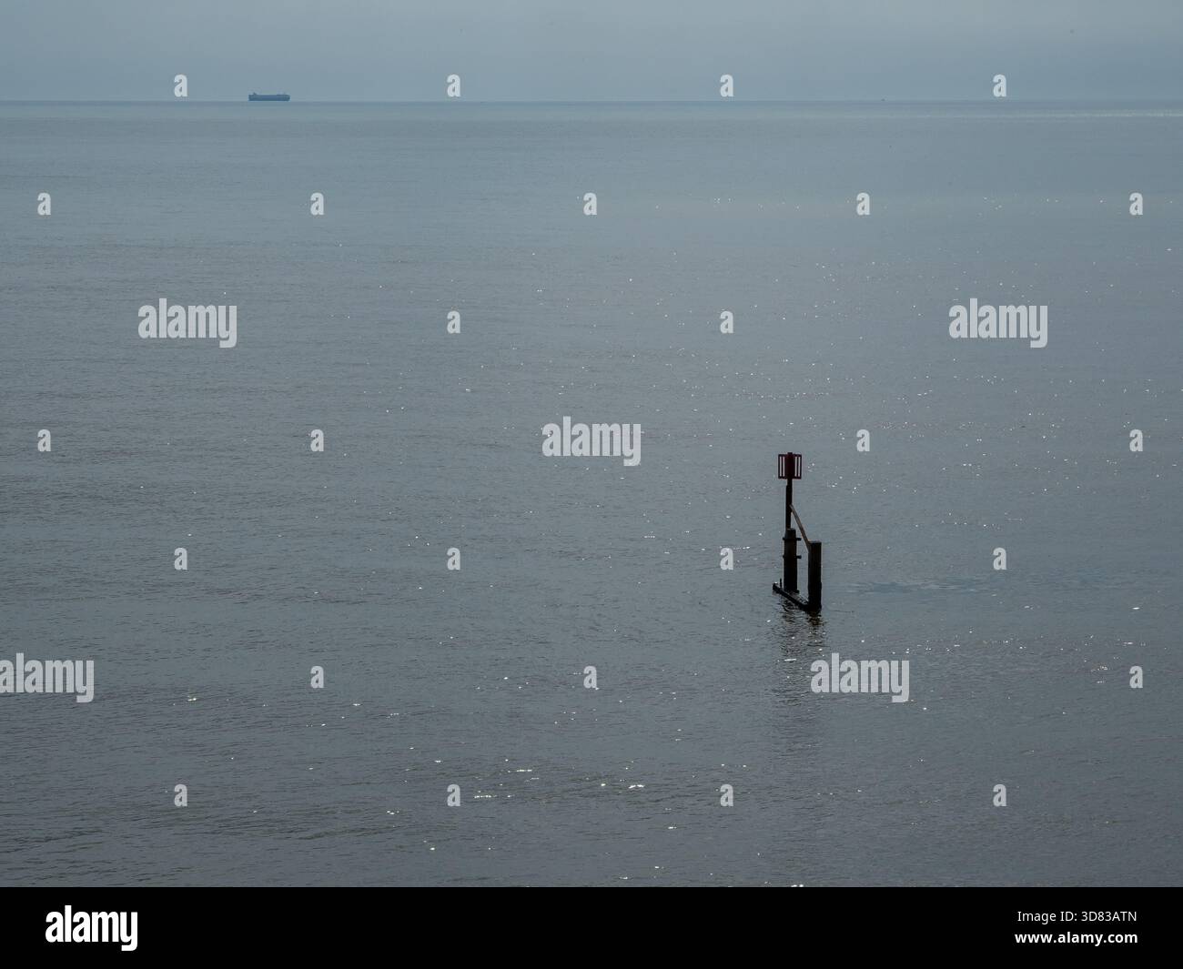 Navigation marker and distant ship on open water Stock Photo