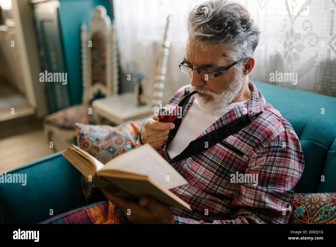 Senior man enjoys reading book while relaxing on sofa Stock Photo