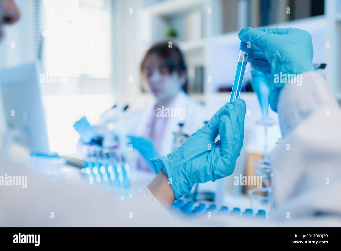 Two female scientists in white lab coats working together in a bright ...
