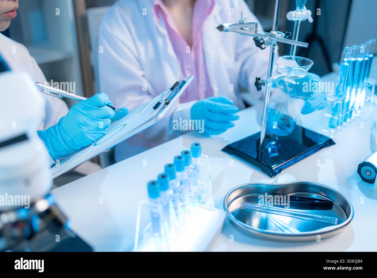 Two chemists in white lab coats working together in a modern laboratory ...