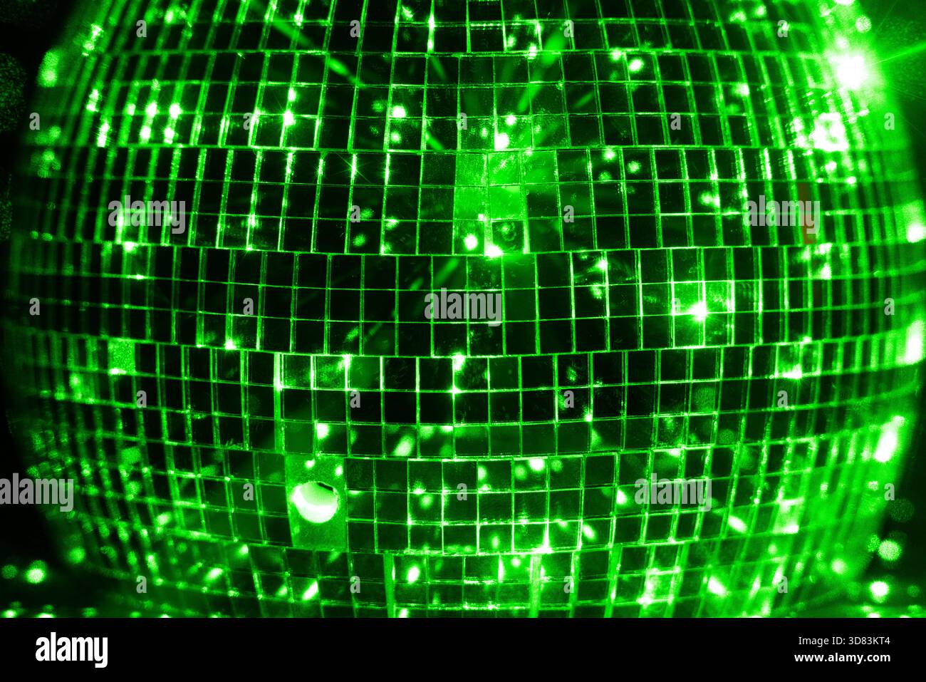 Green lights reflected in disco ball on black backdrop Stock Photo