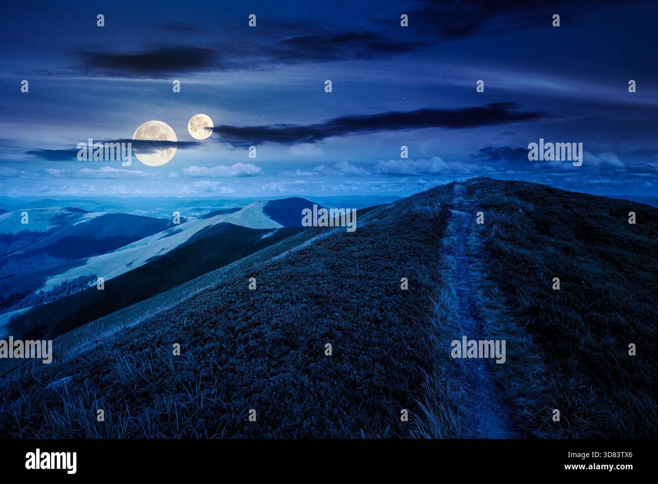 path to the mountain top at night. beautiful summer scenery with dynamic clouds on a dark sky in full moon light. scenic landscape with rolling hills. Stock Photo