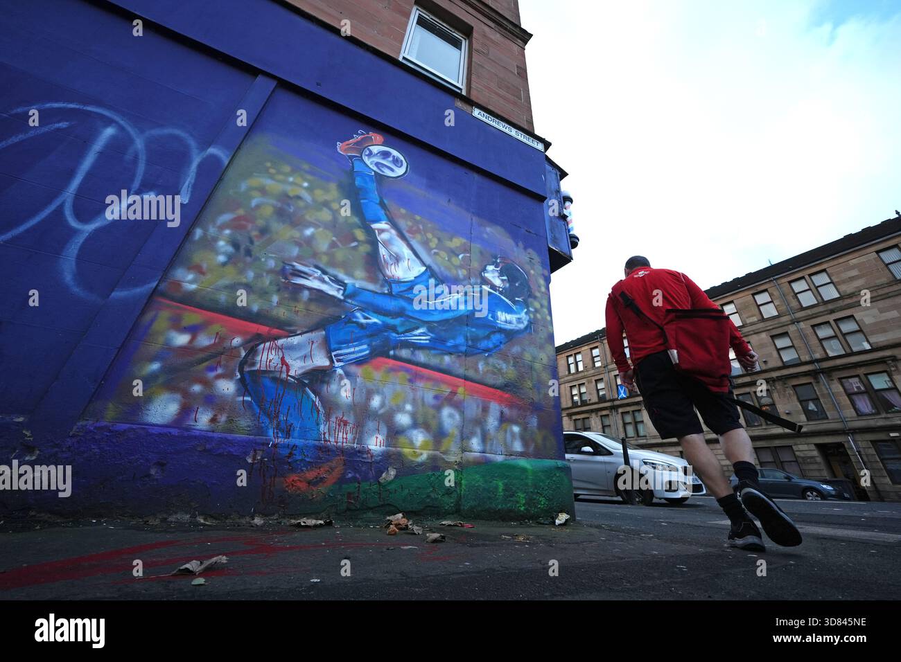 a-postman-walks-past-a-mural-of-scott-mctominay-scoring-an-overhead