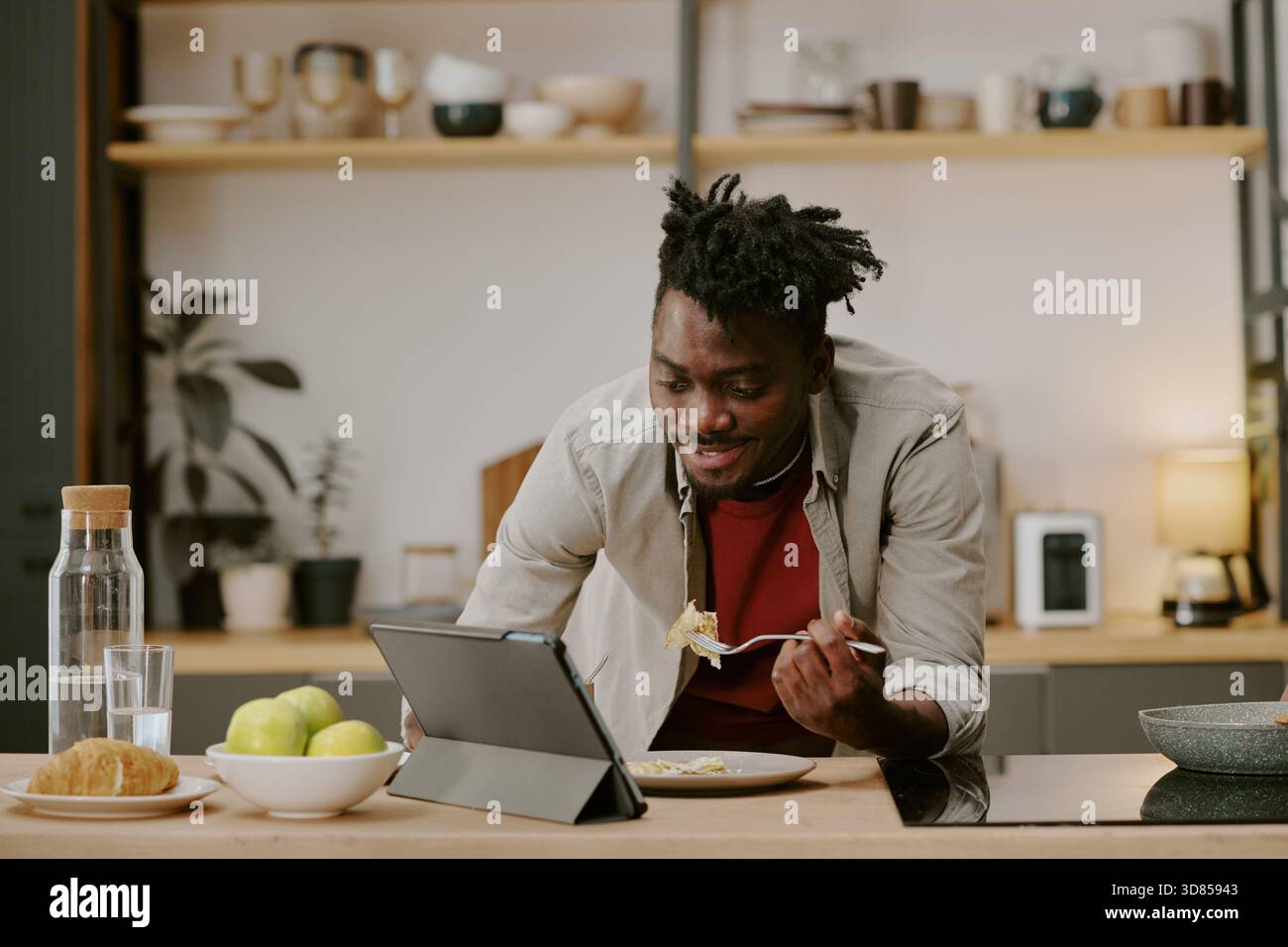 Young Black Man Eating Breakfast While Shopping Online Using Digital Tablet Stock Photo