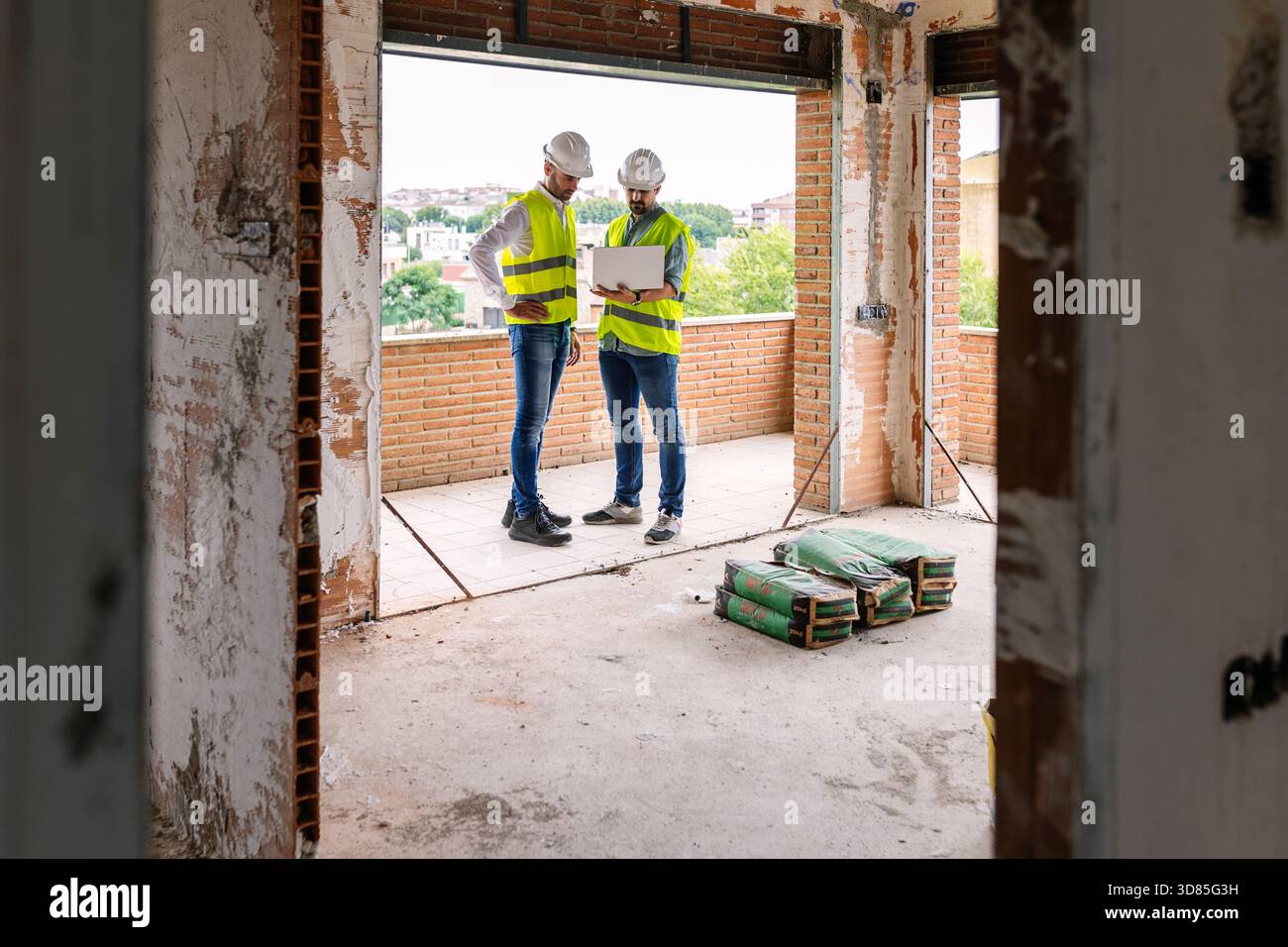 Engineers using laptop discussing project at construction site Stock Photo