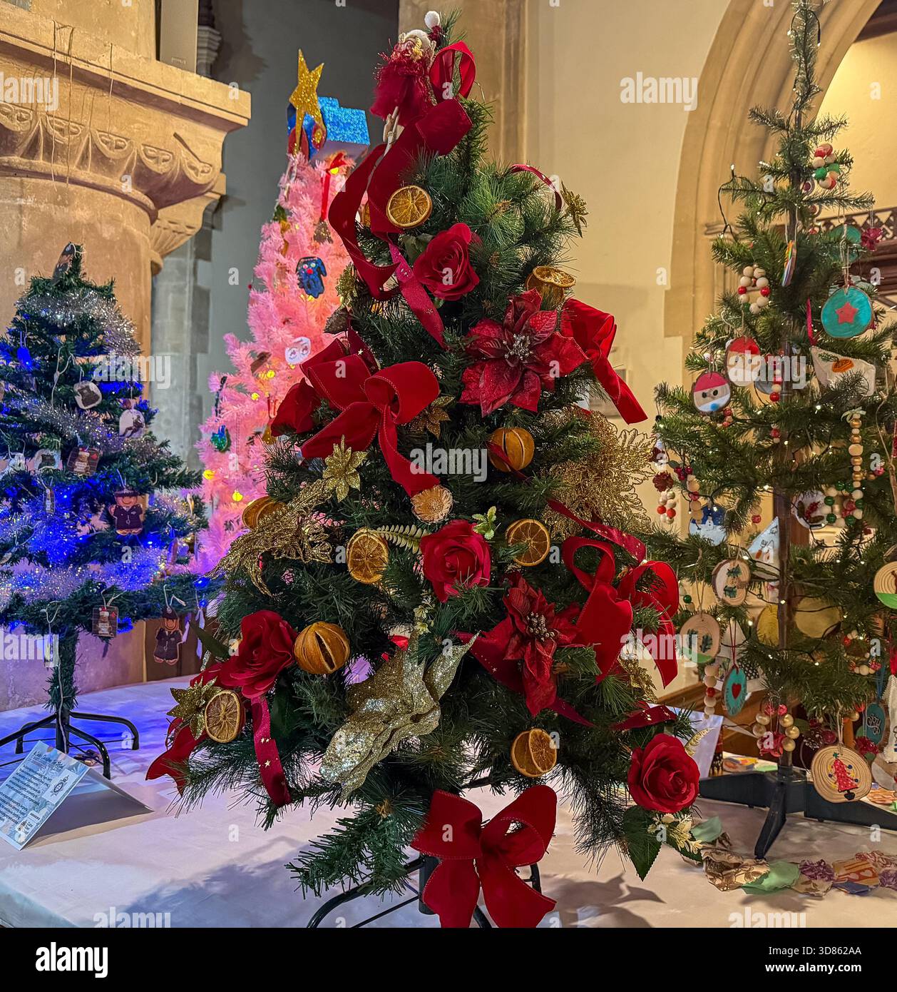 Decorated Christmas trees on display at St Mary's Church Calne Christmas tree festival, featuring ribbons, ornaments, dried fruit. - Smartphone Captured Stock Image