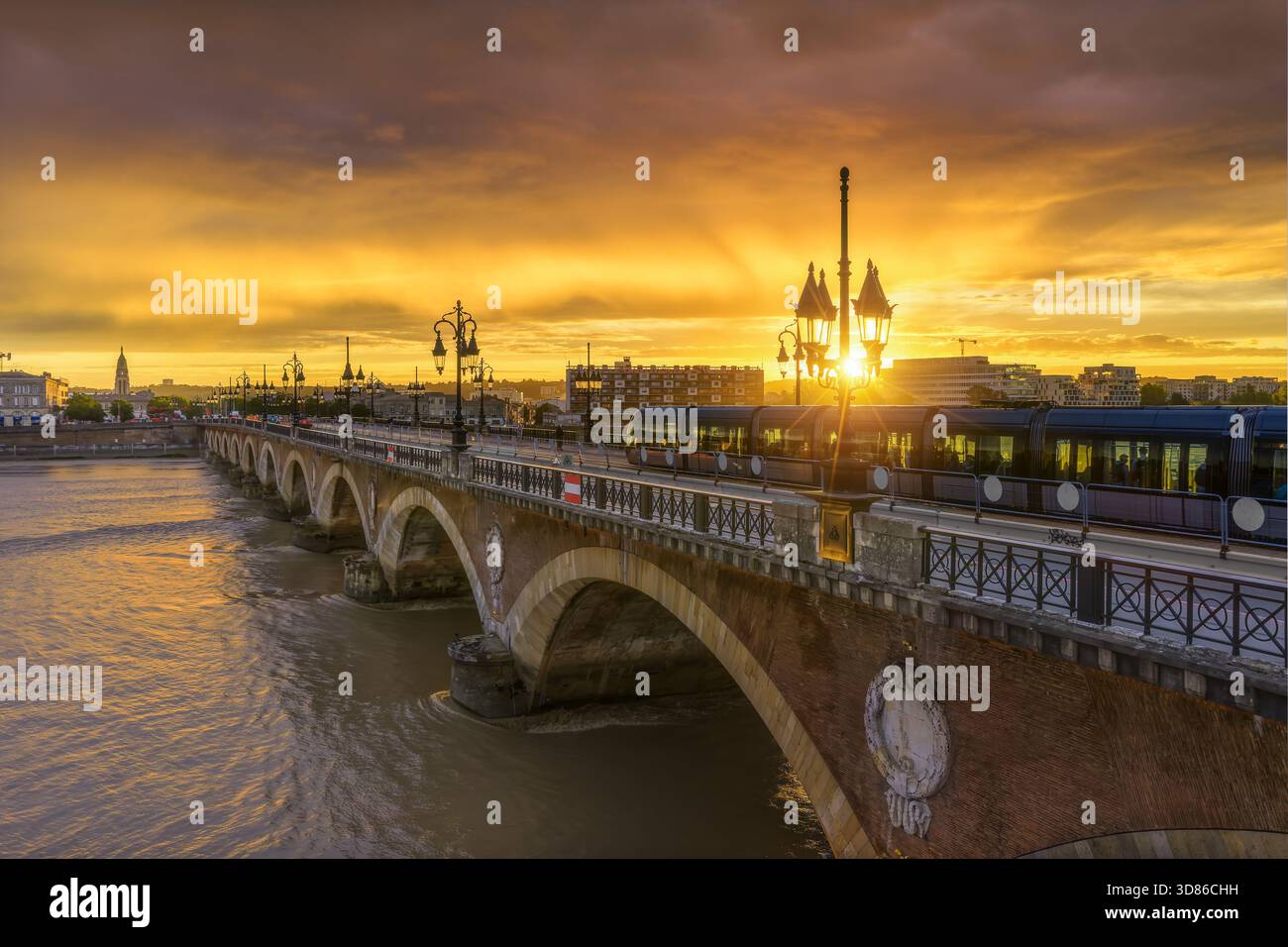 Aerial view of the Pont de Pierre bridge glows with the setting sun over the Garonne River, casting a warm hue on the water, Bordeaux, Nouvelle-Aquita Stock Photo