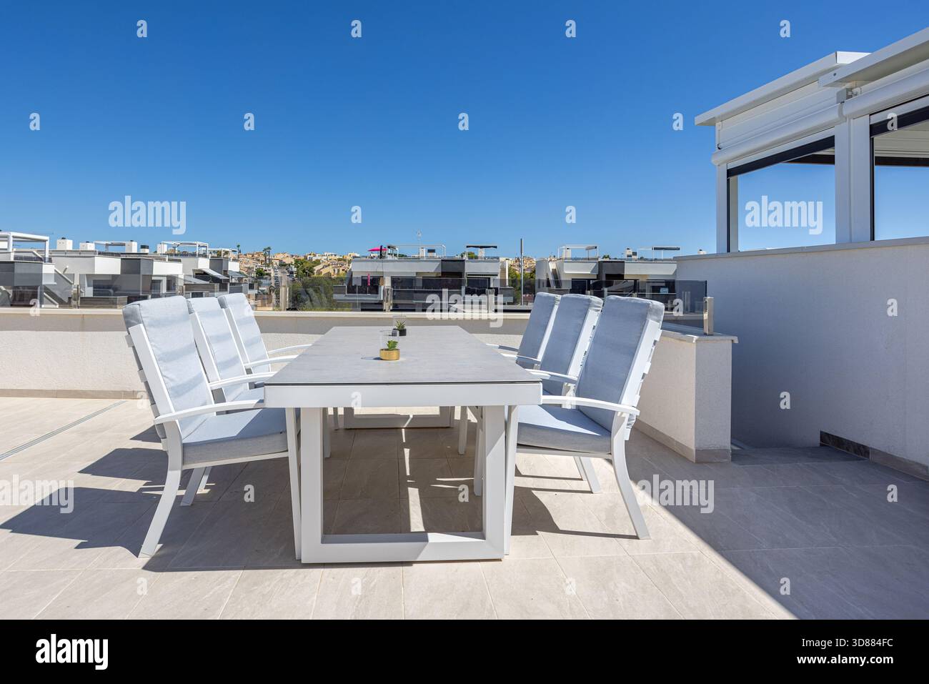 Image showcasing Stylish outdoor dining table with cushioned chairs on rooftop terrace ...